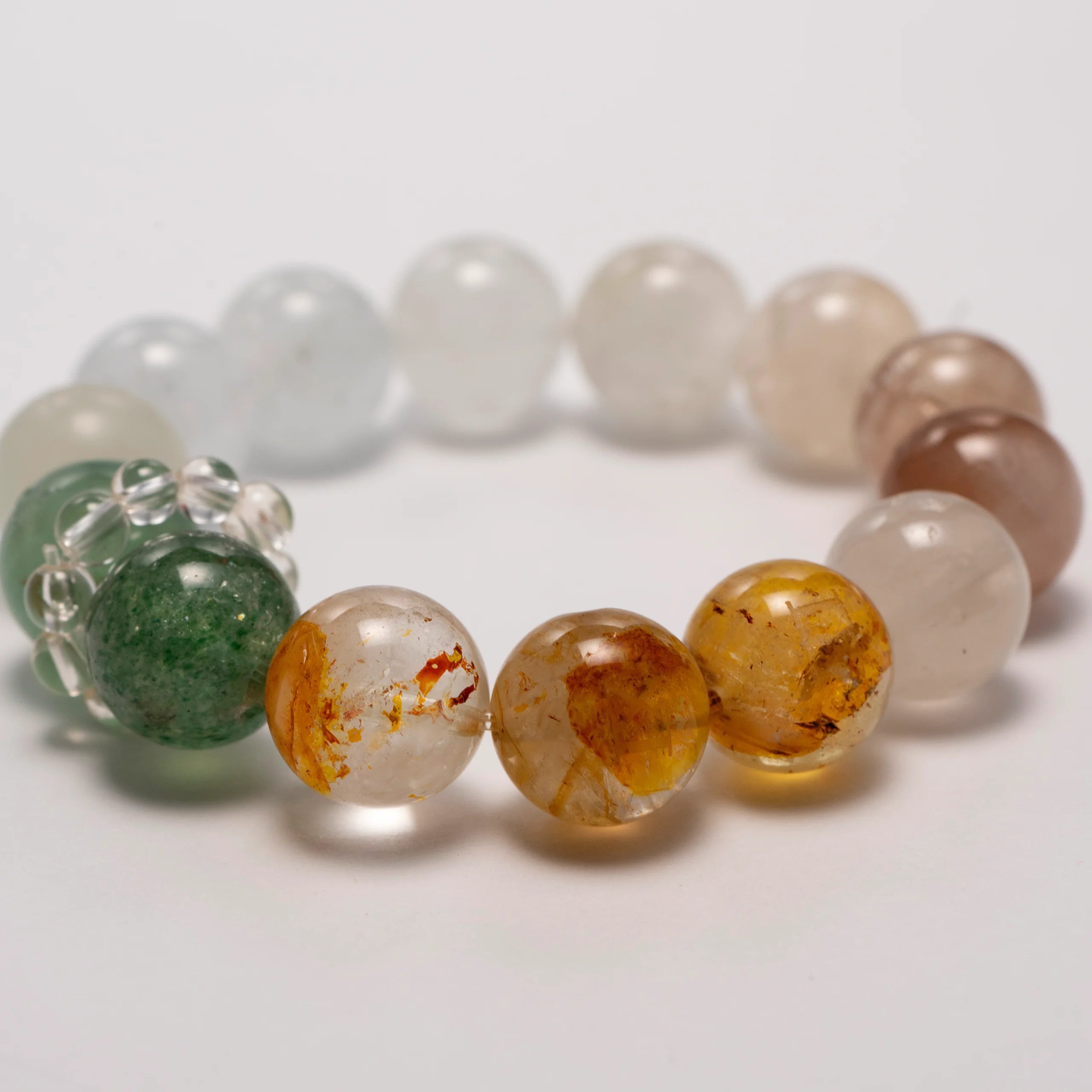 Forest Tempo Garden Quartz & Green Strawberry Quartz Bracelet laid flat in a circular arrangement, showing all seven gemstone colors.