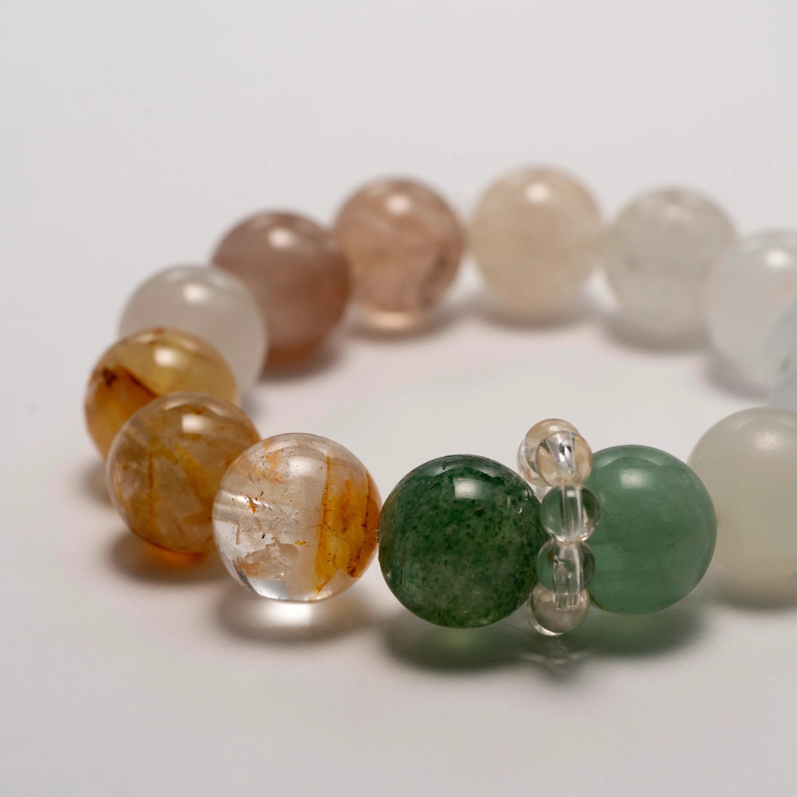 Forest Tempo Garden Quartz & Green Strawberry Quartz Bracelet laid flat in a circular arrangement, showing all seven gemstone colors.